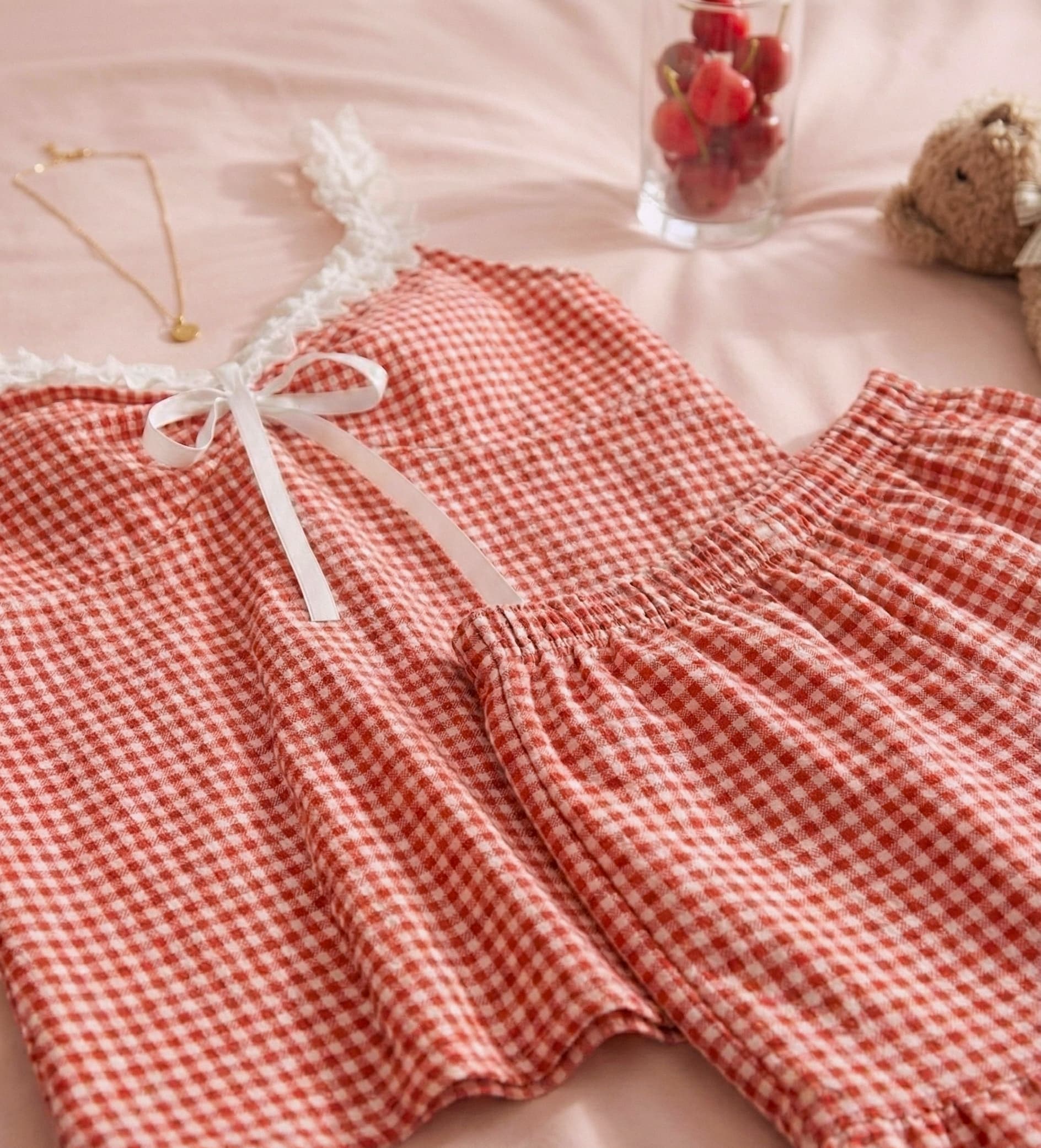 Red patterned pajama set with lace trim on a pink surface.