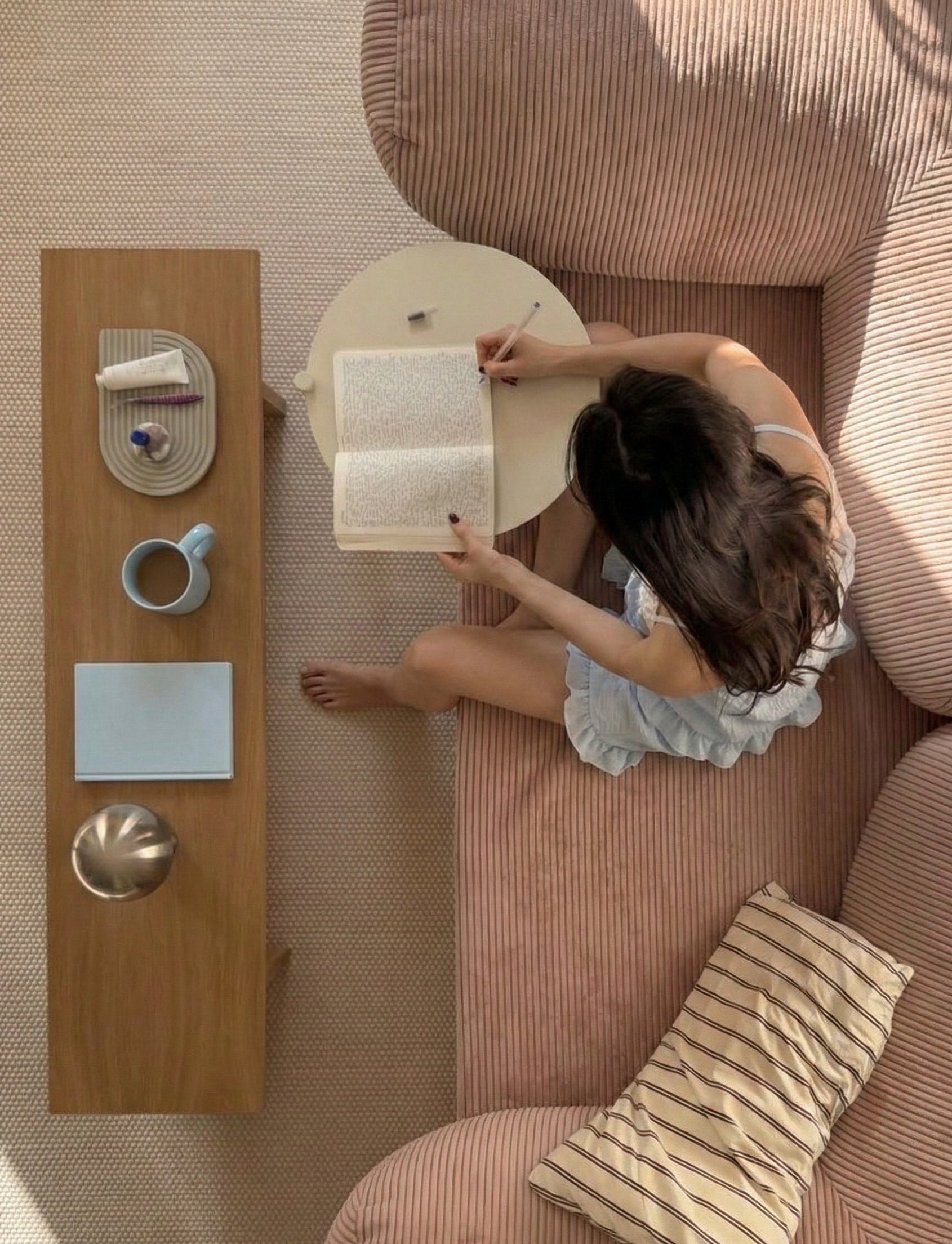 Person reading a book on a couch with a small table beside them