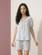 Woman wearing a light blue pajama set with a collar against a plain background