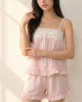Woman wearing a pink lace pajamas set against a white background