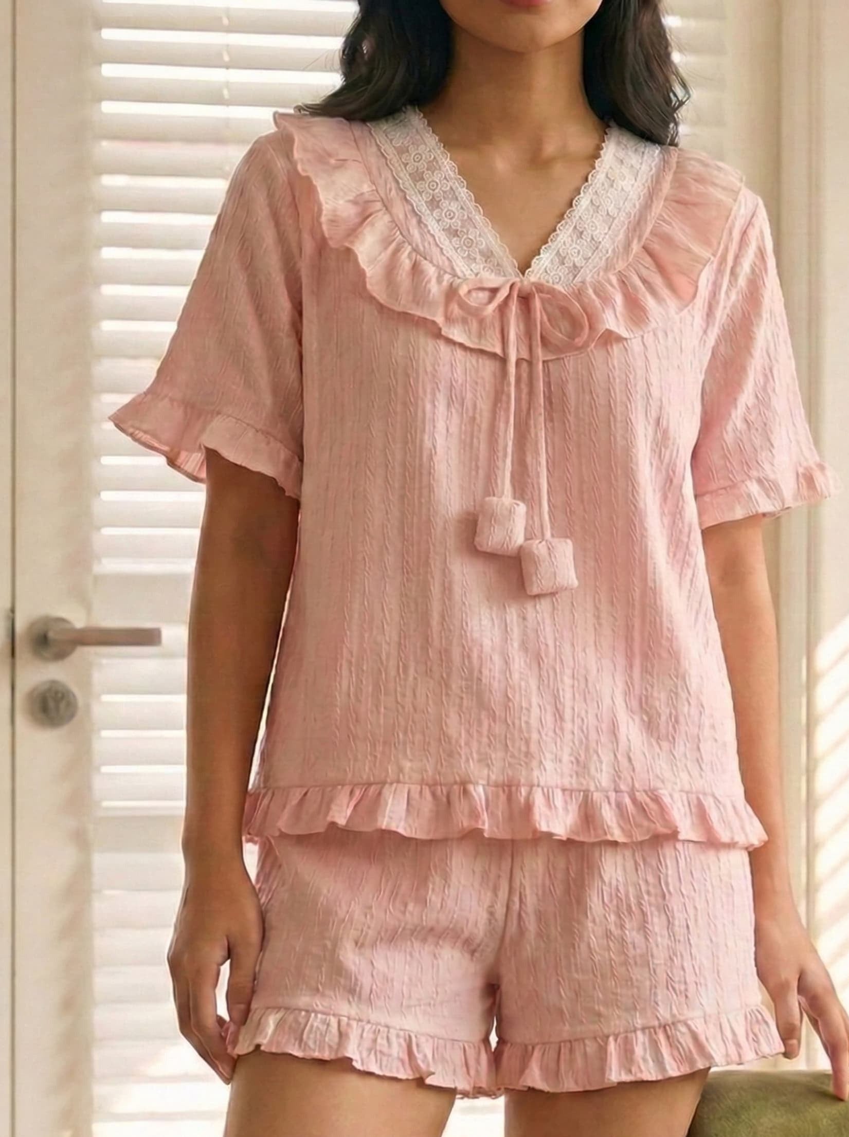 Pink pajama set with ruffles and lace details worn by a person.